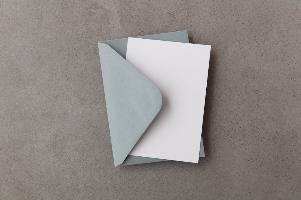 Flat lay of a blue envelope with an open blank card on concrete texture.